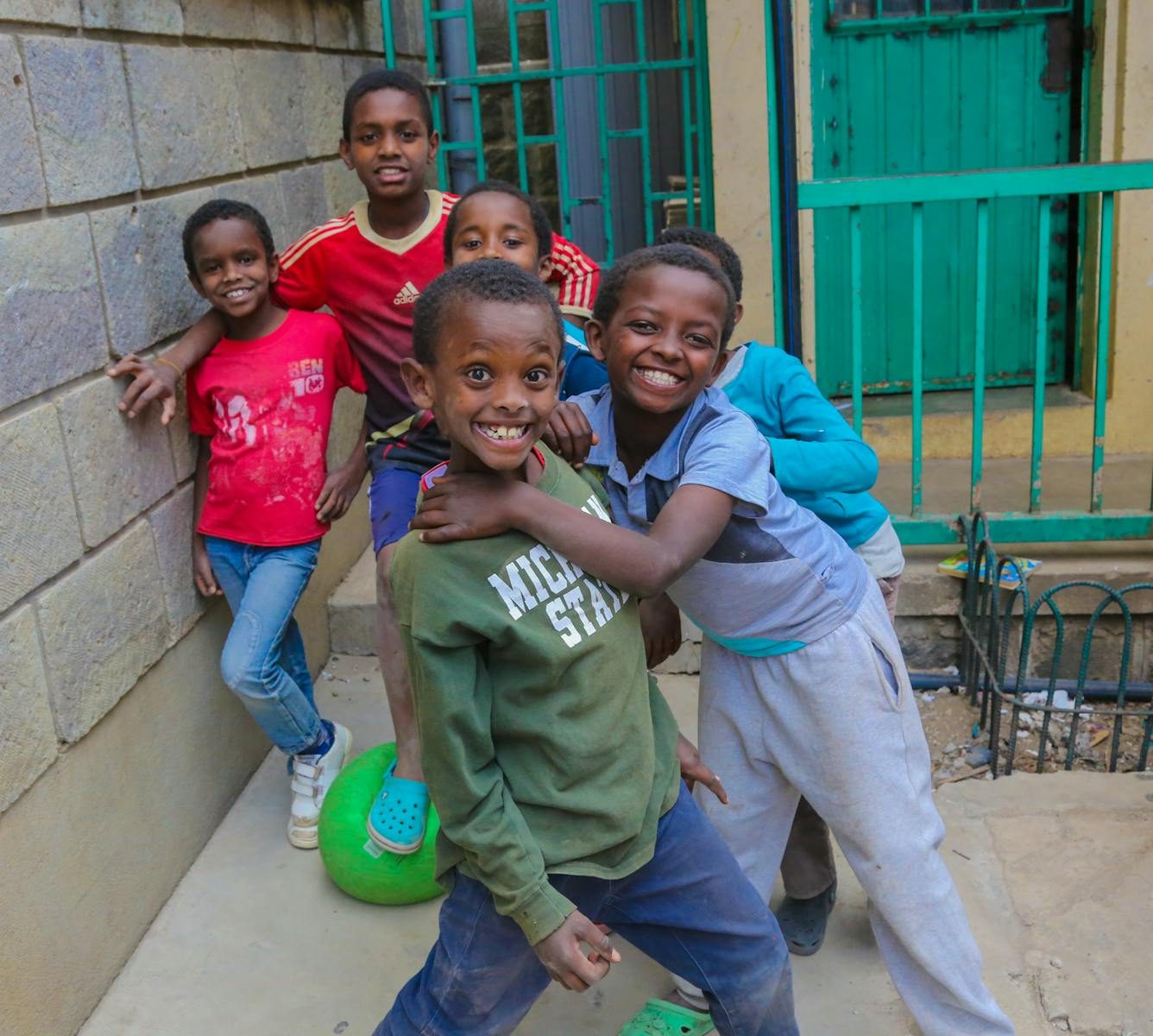 Group of happy children playing outdoors in an urban setting, smiling and posing for the camera.
