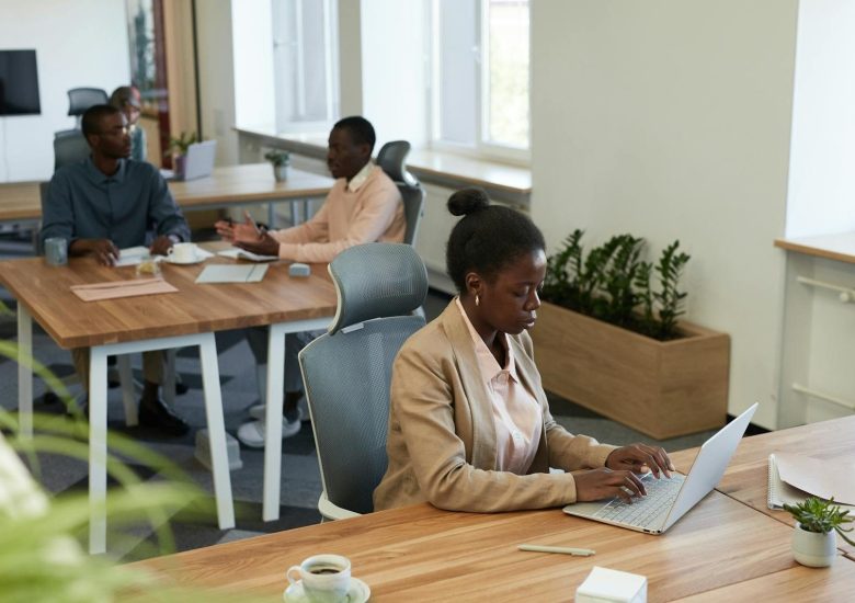 Diverse group of professionals collaborating in a modern office setting with laptops and discussions.